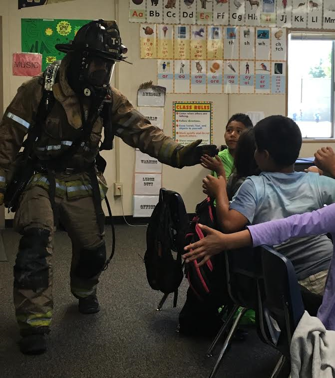 firefighter in full gear speaking to classroom